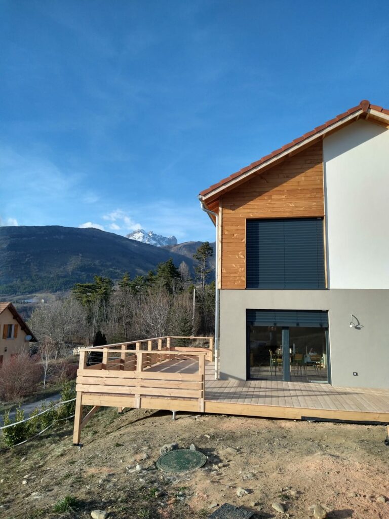Maison en ossature bois bardage en douglas, mélange de crépis - Abri voiture en douglas - Terrasse en douglas - Intradosse Hautes-Alpes